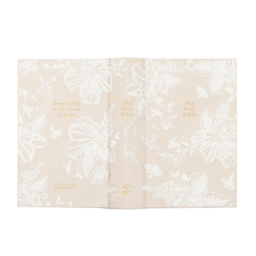 Beige fabric Bible with white floral patterns and gold text on a white background