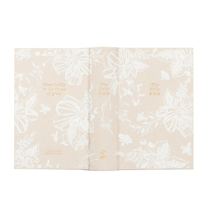 Beige fabric Bible with white floral patterns and gold text on a white background