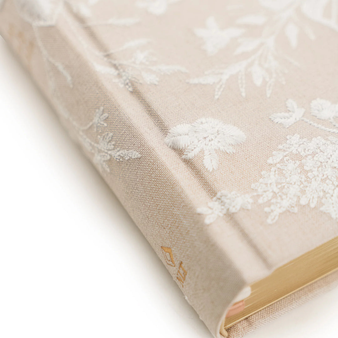 Beige fabric Bible with white floral embroidery on a white background