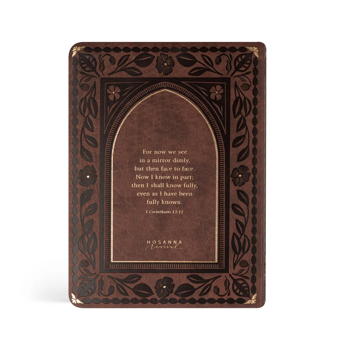 Brown leather Bible with embossed floral design and gold scripture text on a white background