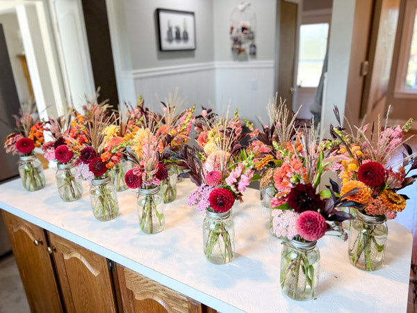 Assorted floral arrangements in mason jars on a kitchen counter.