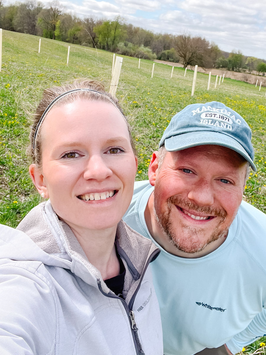 Two people taking a selfie in a grassy field with trees in the background