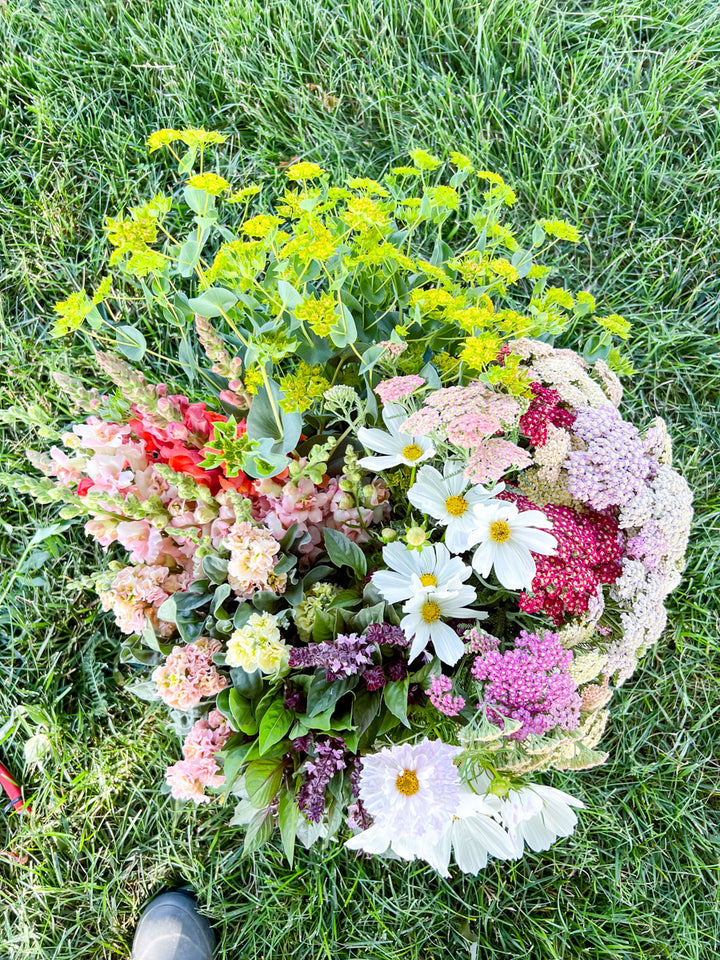 Bucket of mixed flowers sitting on grass