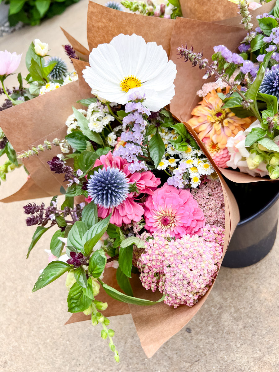 Bouquet of colorful flowers wrapped in brown paper on a concrete surface