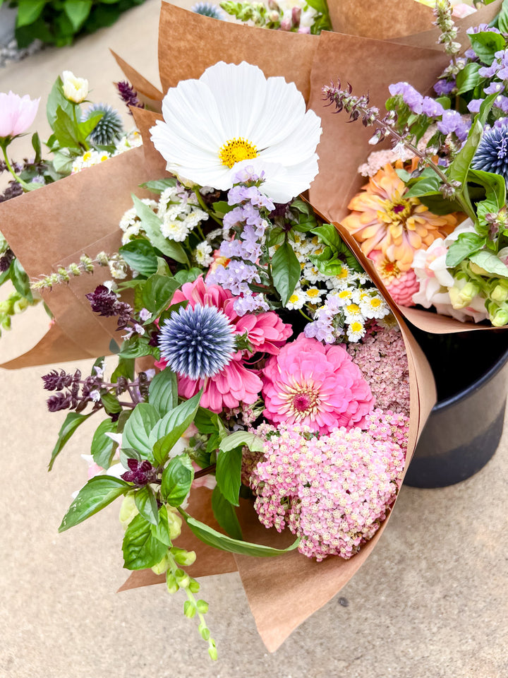 Bouquet of colorful flowers wrapped in brown paper on a concrete surface