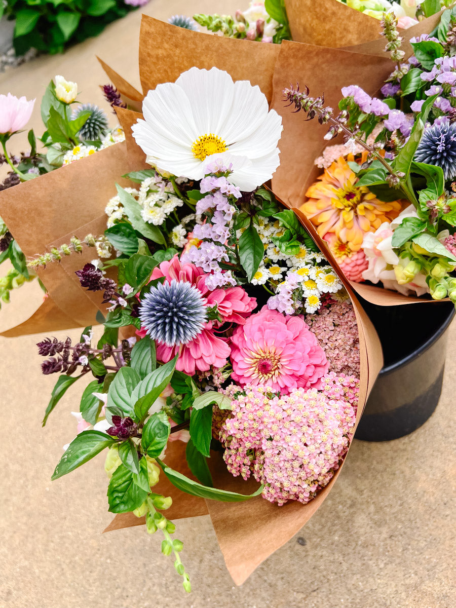 Bouquet of flowers wrapped in brown paper on a concrete surface