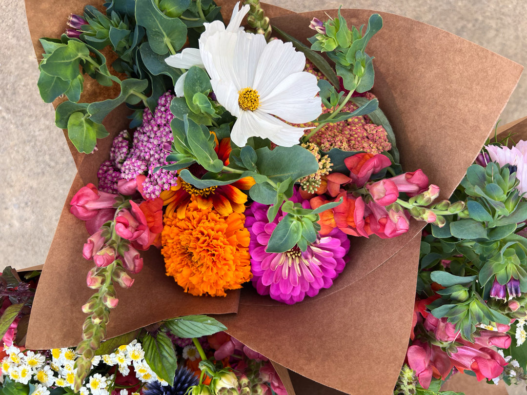 Bouquet of colorful flowers wrapped in brown paper on a neutral background