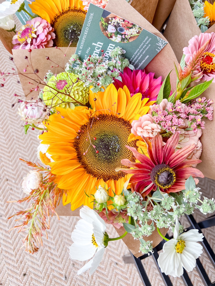 Bouquet of flowers with a sunflower and other colorful blooms on a textured surface.
