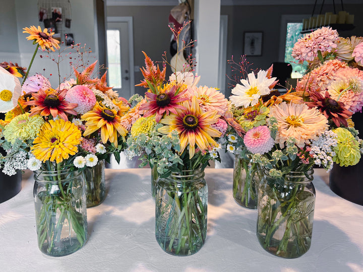 Bouquets of flowers in jars on a table in a home setting