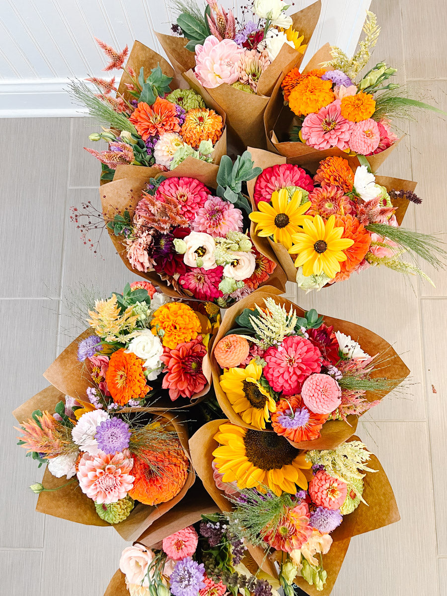 Colorful flower bouquets in brown paper packaging on a light background