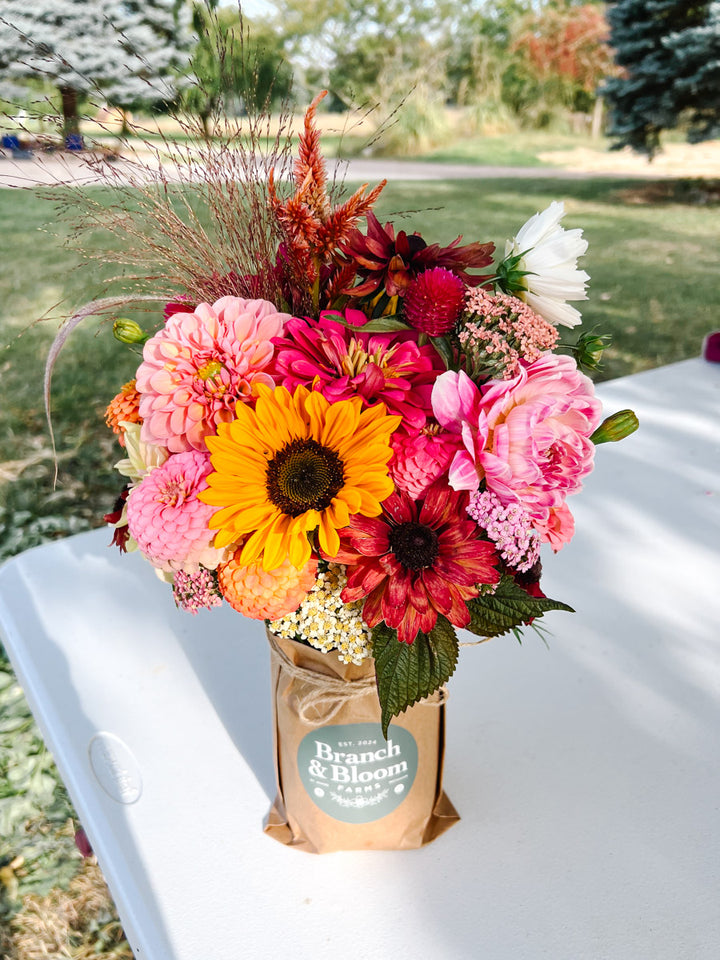 Custom mason jar arrangement featuring a colorful palette of pink, yellow and orange flowers