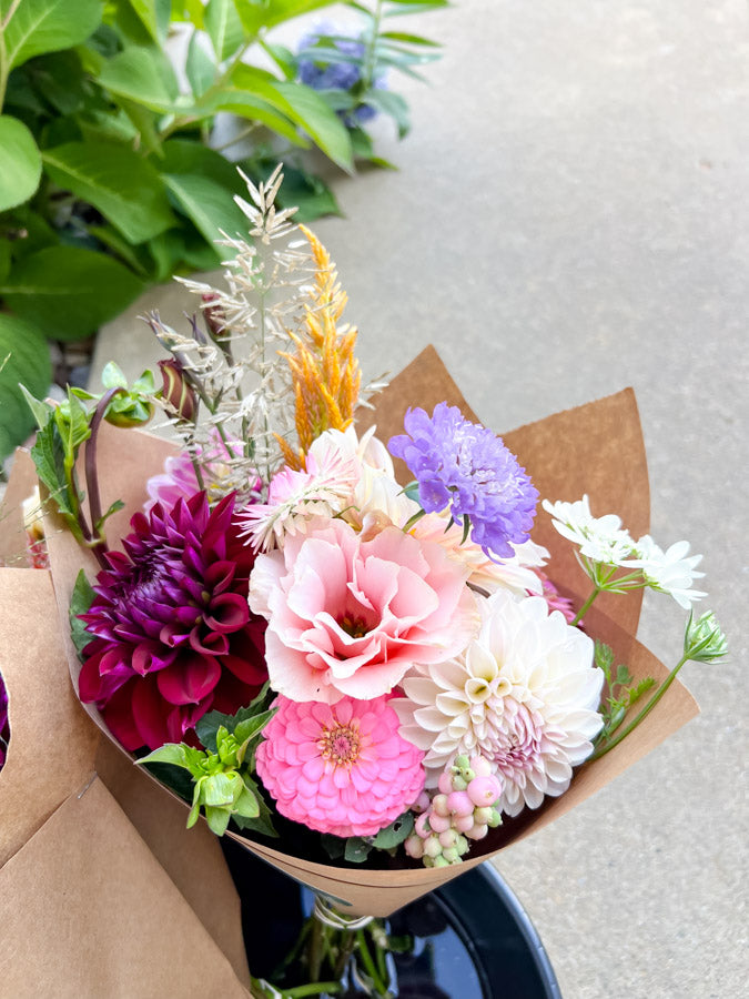 Bouquet of colorful flowers wrapped in brown paper on a light background