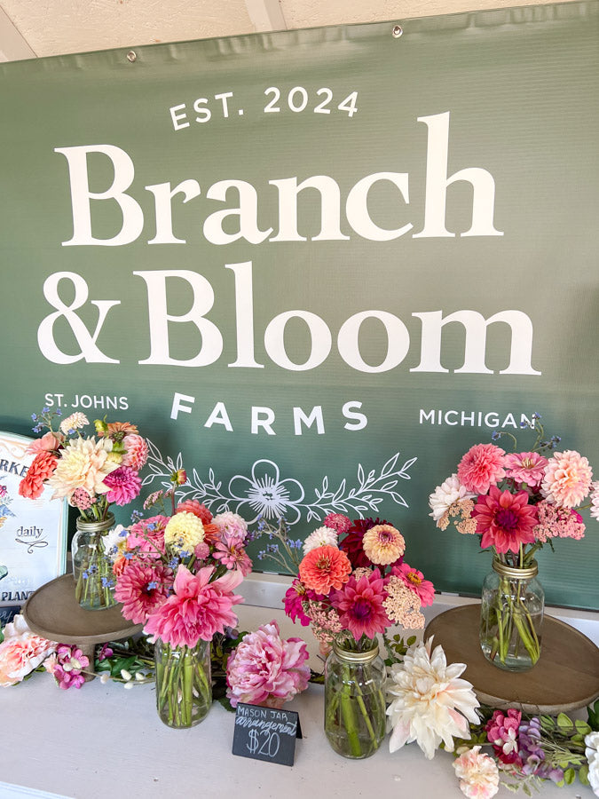 Floral arrangements displayed in front of a 'Branch & Bloom' sign with 'Est. 2024' on a green background.