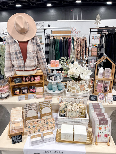 Display of products and stationery items on a table with a person wearing a hat in the background.