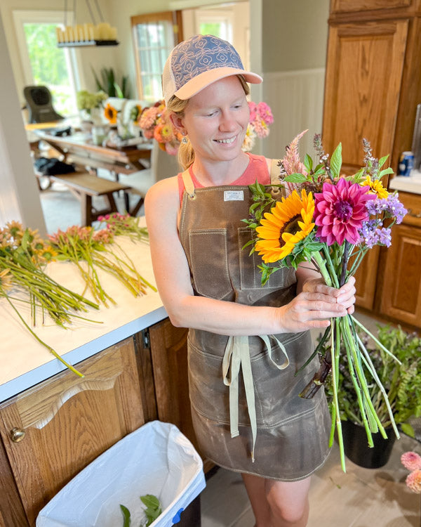 Farmer florist putting together a market bouquet of flowers in a kitchen