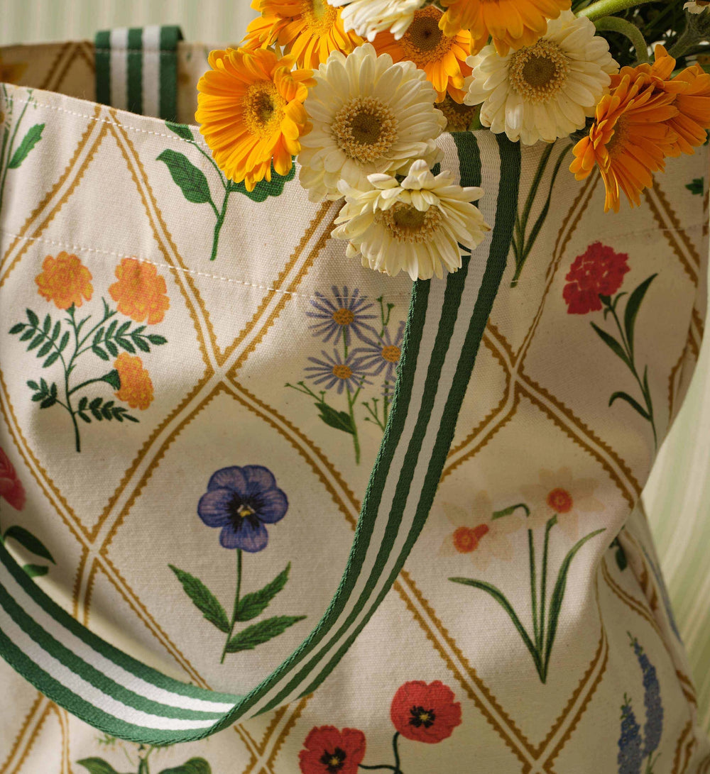 Fabric tote bag with floral patterns and a vase of flowers on a table.