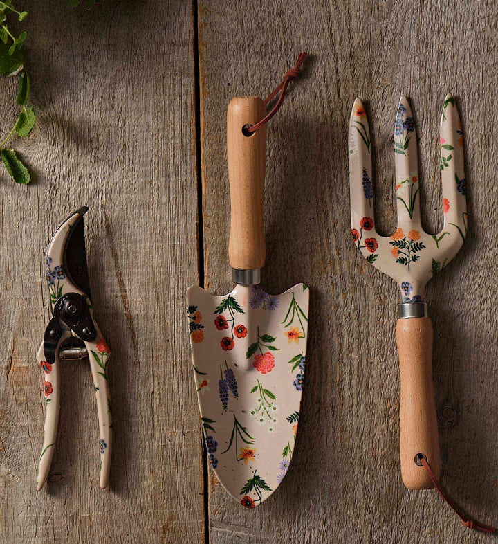 Set of gardening tools with floral patterns on a wooden surface