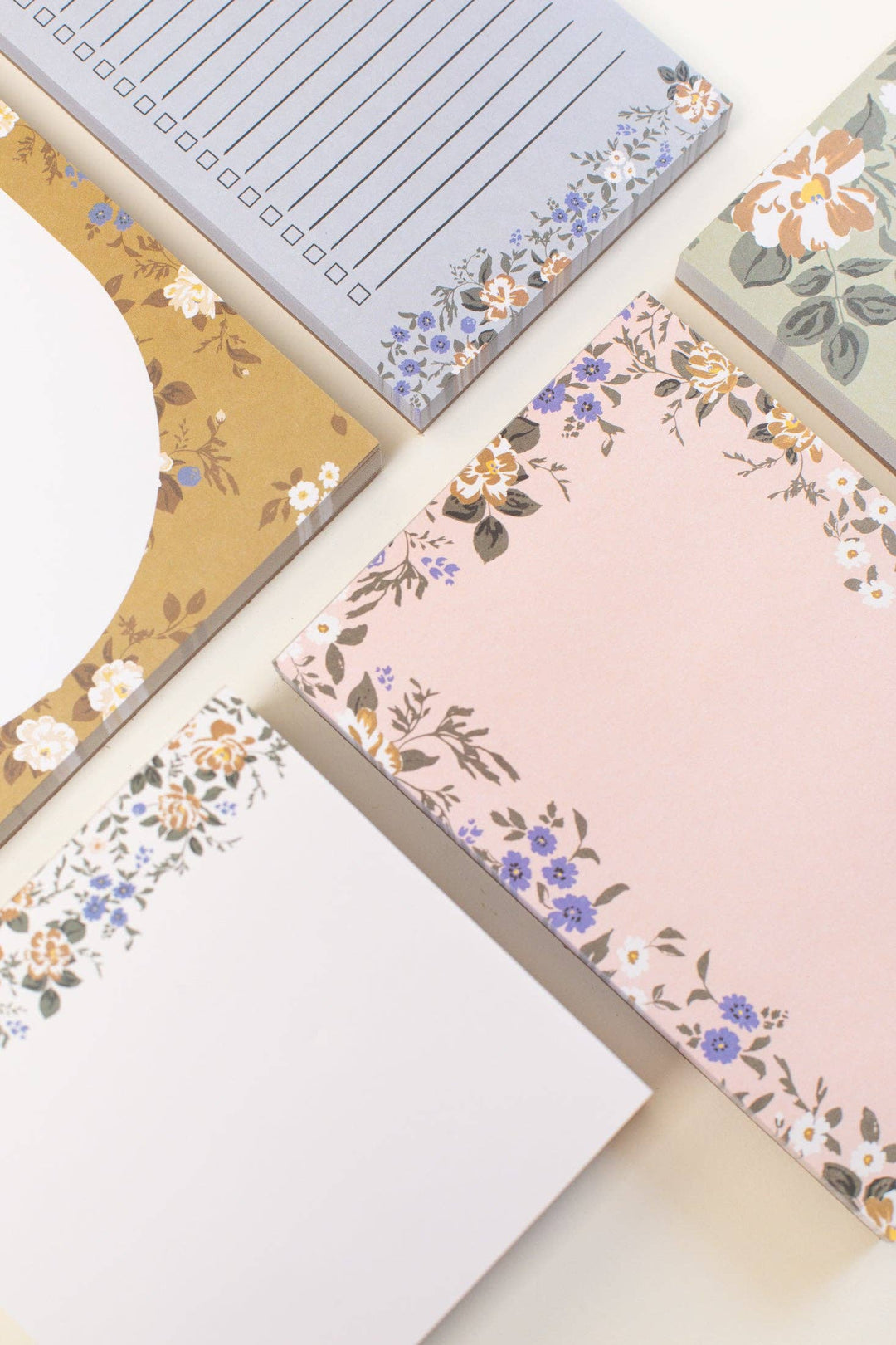 Set of stationery items including notebooks and a notepad with floral designs on a light background.
