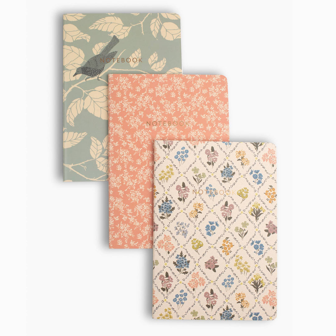 Three patterned notebooks stacked on a white background