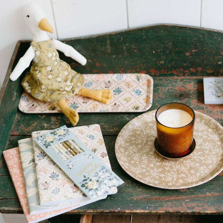 Vintage-style table with a candle, books, and a plush duck toy on a white tiled wall background.