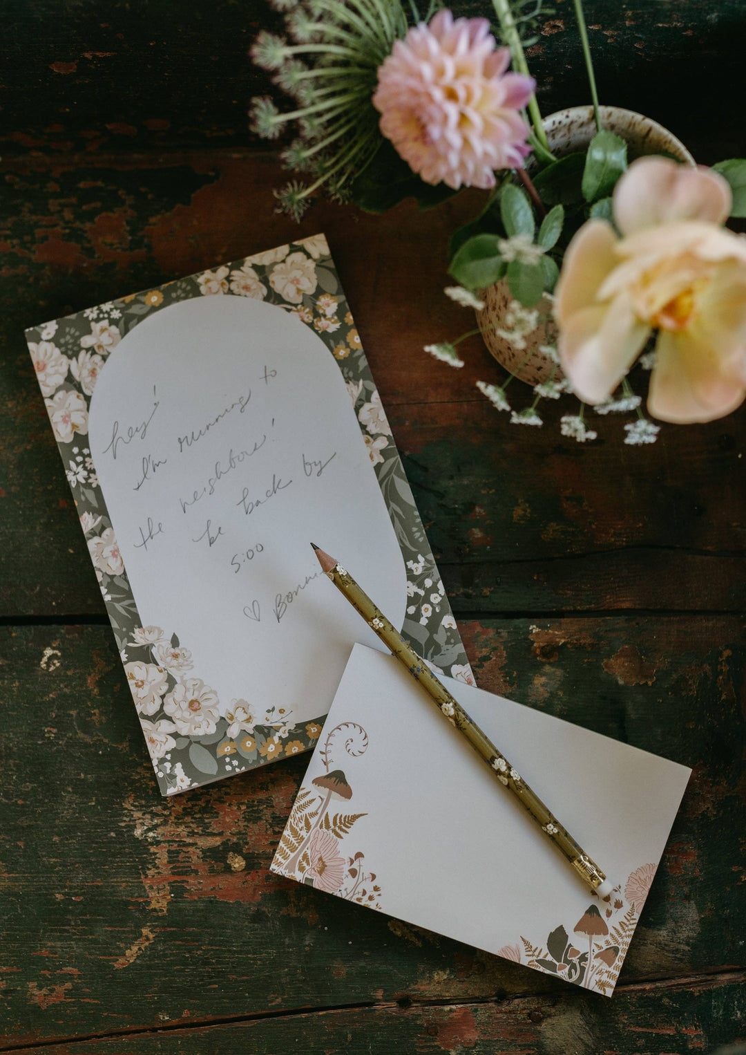 Floral stationery set with a pencil on a rustic wooden surface