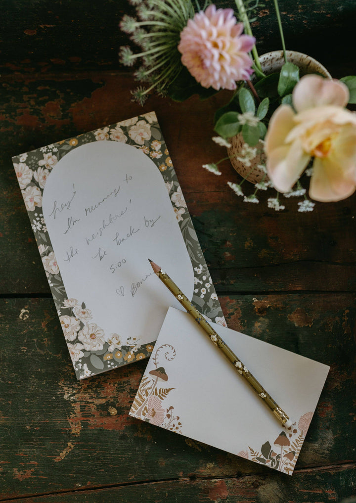 Floral stationery set with a pencil on a rustic wooden surface