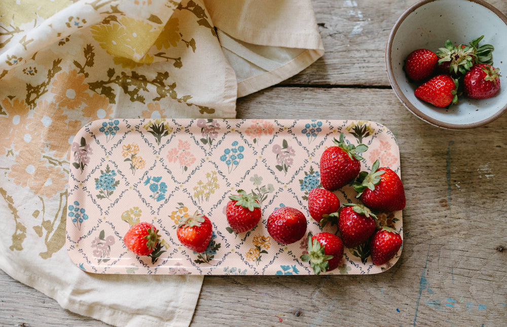Strawberries on a decorative tray with a bowl of strawberries on a wooden surface