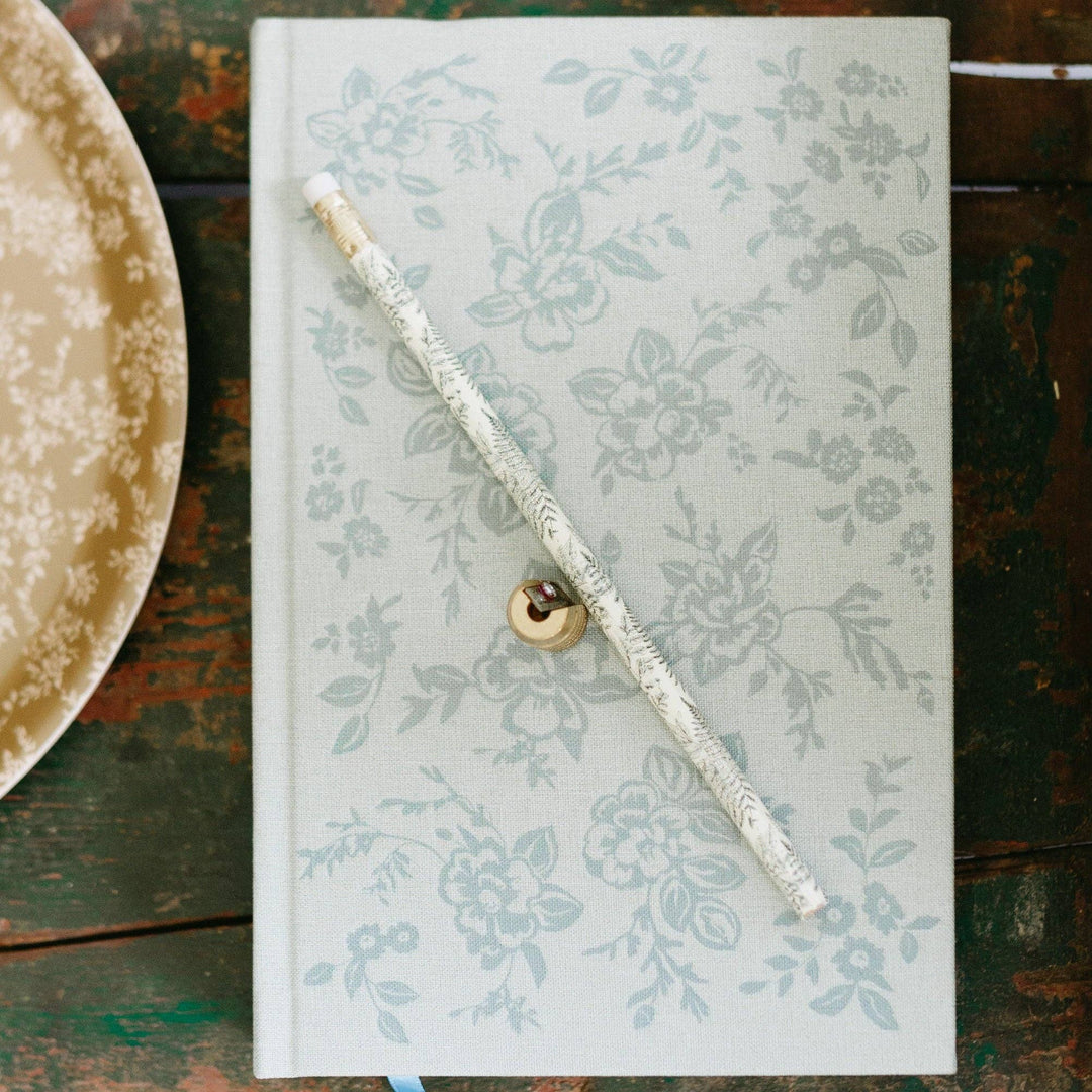 Floral-patterned notebook with a pen on a rustic wooden surface