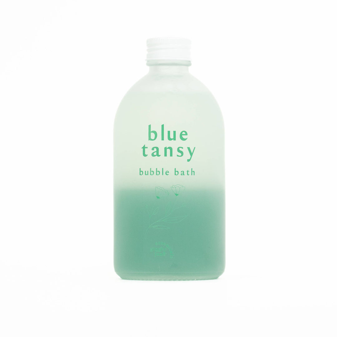 Bottle of blue tansy bubble bath with gradient design on a white background
