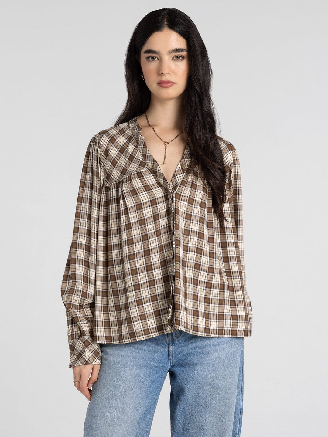Woman wearing a plaid shirt and jeans on a plain background